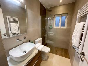 uma casa de banho com um lavatório, um WC e um espelho. em Iris em Atenas