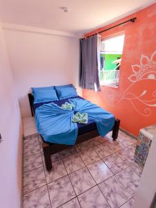 um quarto com uma cama com lençóis azuis e uma janela em Mundo da Lua Hostel em Morro de São Paulo