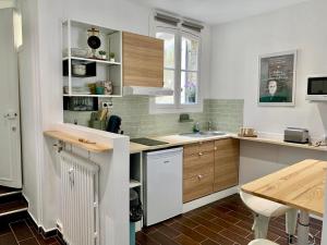 a kitchen with white cabinets and a wooden table at "Chez Anne à la Plage" Studio à 150 m de la Plage in Trouville-sur-Mer