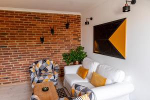 a living room with two white couches and a brick wall at Apartamenty Sudeckie nad zalewem II in Sosnówka