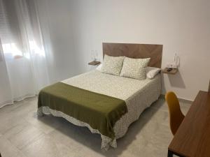 1 dormitorio con 1 cama con manta verde y almohadas en Suites Benalup Centro, en Benalup-Casas Viejas