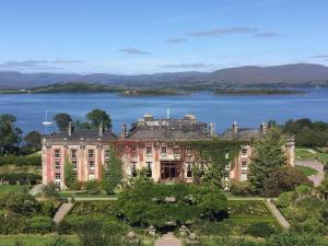 a large mansion with a lake in the background at Berlin Wall Apartment at The Residence Bantry in Bantry