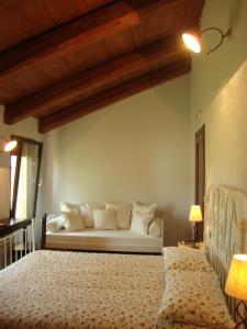 1 dormitorio con cama blanca y sofá en Agriturismo L'Unicorno, en Portomaggiore