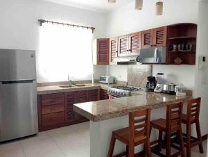 eine Küche mit einem Kühlschrank und einer Theke mit Stühlen in der Unterkunft Apartment Tortugas - rooms with AC and great pool at 5 min from Carrizalillo beach and Benito Juarez Bulevard in Puerto Escondido