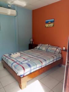 a bedroom with a bed with an orange wall at Surfari Bocas in Bocas Town