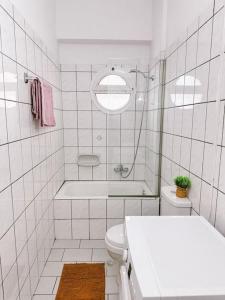 a white bathroom with a tub and a toilet at SeaSideRooms in Ierápetra