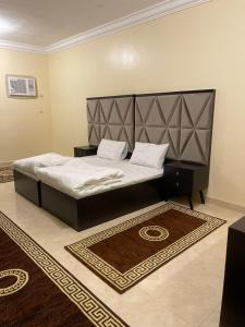 a bedroom with a bed with a large headboard and a rug at فندق الفيصلية in Ḩajlah