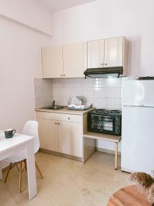 a kitchen with white cabinets and a sink and a refrigerator at SeaSideRooms in Ierápetra