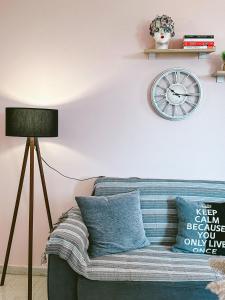 a living room with a couch and a clock on the wall at SeaSideRooms in Ierápetra