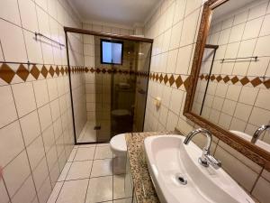 Un baño con lavabo, inodoro y espejo. en Chamonix, en Itapema 10 fotos más