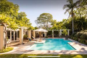 a swimming pool in the backyard of a house at Garden Cottage - Leafy Constantia Guest House in Cape Town