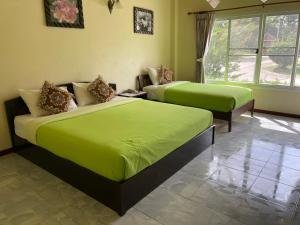 a bedroom with two beds with lime green sheets at ธนวรรณรีสอร์ท - Thanawan Resort in Ban Phra Trong