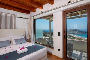 a bedroom with a bed and large windows at Stefanos Village Hotel in Plakias
