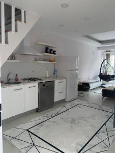 a kitchen with white cabinets and a refrigerator at Denize 800 m uzaklıkta villamız in Aksu