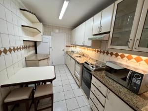 Una cocina con gabinetes blancos y encimera. en Chamonix, en Itapema