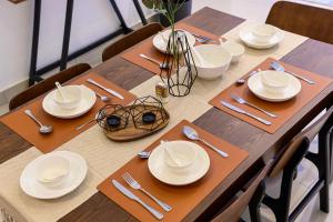 a wooden table with white plates and silverware on it at Serene Mossy Family Cottage(2-7pax) 10 Min to BOH in Cameron Highlands
