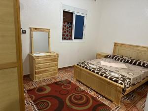 ein Schlafzimmer mit einem Bett, einem Spiegel und einer Kommode in der Unterkunft إقامة الامل in Beni Mellal