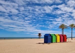 a row of colorful beach huts on a beach with palm trees at veronica in Llaurí +7 photos