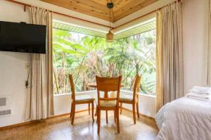 a bedroom with a bed and two chairs and a window at Kilauea iki- Hale Kumu La'au in Volcano