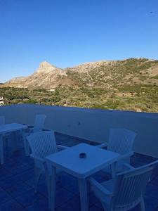 a row of tables and chairs with a mountain in the background at Iliachtida apartments in Philotium