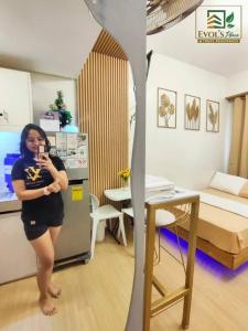 une femme prenant une photo d'une pièce dans l'établissement Trees Residences Staycation Evol's Place, à Manille