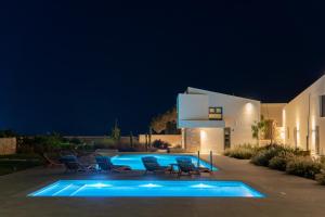 a swimming pool in front of a house at night at Itida Suites in Sitia