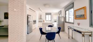 a kitchen with a table and blue chairs in a room at BnBIsrael Apartments - Hakovshim Marguerite in Tel Aviv