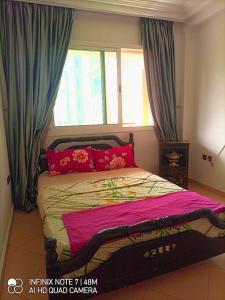 - une chambre avec un lit doté d'oreillers rouges et une fenêtre dans l'établissement appartement de vacances, à Kenitra