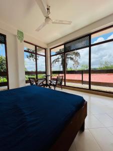 a bedroom with a blue bed and large windows at TheLakeHostel in Hikkaduwa