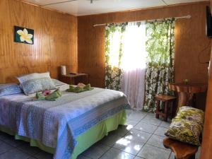 um quarto com uma cama e uma janela em Cabanas Hinariru Nui em Hanga Roa