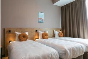 two beds in a hotel room with white sheets at Distrikt Hotels Amsterdam Zaandam in Zaandam