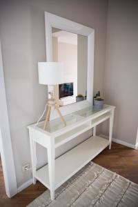 a white dressing table with a mirror and a lamp at Appartement du Mont de L’Enclus in Buisestraat