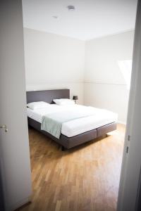 a bedroom with a white bed and a wooden floor at Appartement du Mont de L’Enclus in Buisestraat