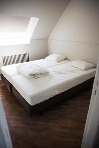 Una cama con sábanas blancas y almohadas en un dormitorio en Appartement du Mont de L’Enclus, en Buisestraat