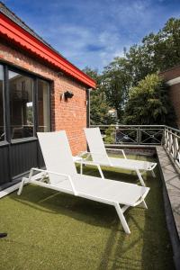 2 weiße Sessel auf einer Terrasse in der Unterkunft Appartement du Mont de L’Enclus in Buisestraat