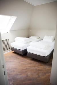 twee bedden in een kamer met witte muren en houten vloeren bij Appartement du Mont de L’Enclus in Buisestraat