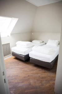 two beds in a room with white walls and wood floors at Appartement du Mont de L’Enclus in Buisestraat