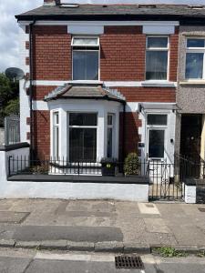 a red brick house with a white front porch at Adanhouse-stockland spacious 5 bedroom house sleeps 12 private garden in Cardiff