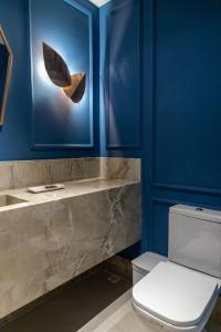 a bathroom with a toilet and a blue wall at Pousada e Cerimonial Itamaraty in Pedra Azul