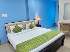 a bedroom with a large bed with green pillows at Classic Hotel in Shamshabad