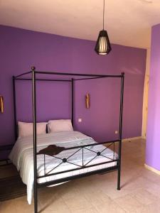 1 dormitorio con 1 cama con pared morada en HÔTEL ETOILE DU SUD en Saint-Louis