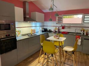 a kitchen with a small table and yellow chairs at Villa Norah t5 duplex in Le Robert