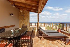 een patio met een tafel en stoelen en de oceaan bij Pension Lucy in Panormos Rethymno