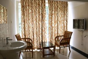 a bathroom with a sink and chairs and a window at Uthradam towers in Trivandrum