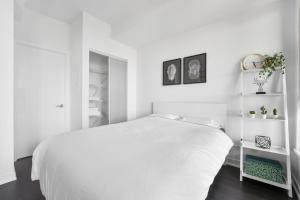 a white bedroom with a white bed and white shelves at Heart of Downtown Toronto! in Toronto