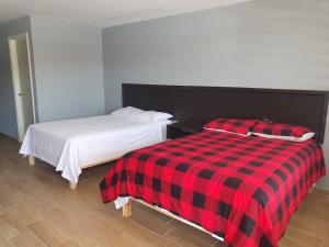 2 camas en una habitación con una manta roja y negra a cuadros en HOSPEDAJE DOÑA ENEDINA, en Ciudad Acuña