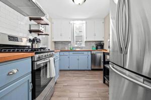 eine Küche mit blauen Schränken und einem Kühlschrank aus Edelstahl in der Unterkunft Neighborhood Home Between The Lakes in Minneapolis