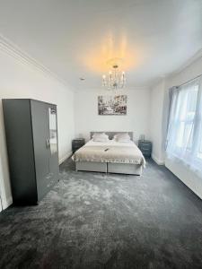 a white bedroom with a bed and a chandelier at Bay Court in Llandudno