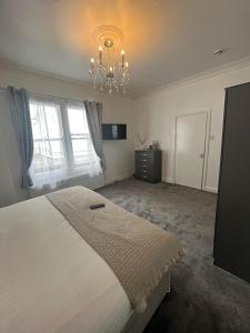 a bedroom with a large white bed and a chandelier at Bay Court in Llandudno