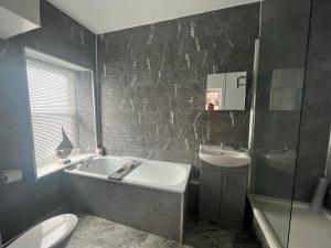 a bathroom with a sink and a tub and a toilet at Bay Court in Llandudno